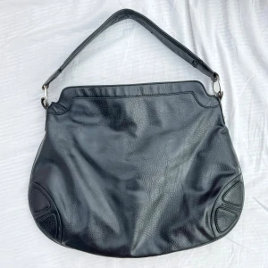 Svart väska, Charmant of Sweden - Snygg svart axelväska från  Charmant of Sweden. Väskan har en praktisk dragkedja på framsidan. Insidan är rymlig med flera fack. Ca 47cm bred & 36cm hög. Kvalitetsutförande. Känns som läder men det är det nog inte. Hämtas på Hägerstensåsen eller ök. 