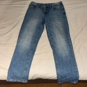 Blå jeans från Jack & Jones Clark - Säljer ett par klassiska blå jeans från Jack & Jones, modell Clark Regular. Jeansen har rak passform, fyra fickor och snyggt ljusblå tvätt. Tillverkade i bomull med traditionell jeanslook och normal midja. Perfekta för en avslappnad stil.