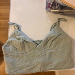 Ljusgrön linnetopp med knytaxelband - Supersöt ljusgrön linnetopp från New yourker med smala axelband som knyts upptill. Toppen har en lätt v-ringad form och är sydd i ett svalt linnematerial, perfekt för varma dagar. Enkel och stilren design som är lätt att matcha.