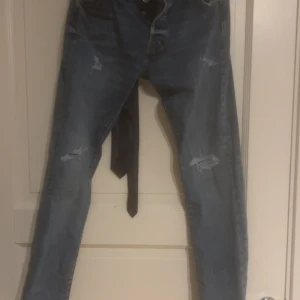 Blå slitna skinny jeans 30/32 - Säljer ett par blå slim fit jeans med slitningar på benen. Jeansen har klassisk femficksdesign och är i stretchigt denimtyg. Perfekta för dig som gillar en smal passform och lite ruffig look.köpta på Jack and Jones för cirka 1000