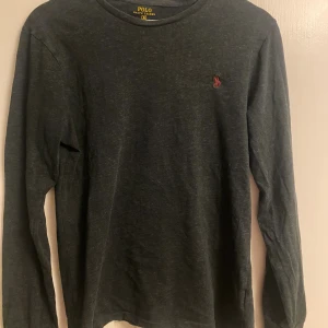 Mörkgrå långärmad tröja Polo Ralph Lauren - Snygg mörkgrå långärmad tröja från Polo Ralph Lauren i bomull. Den är lite tunnare i material och perfekt för layering. Kom med frågor eller bud!