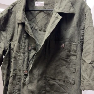 Grön overshirt från Zara - Säljer en grön overshirt från Zara med stora bröstfickor och knappar framtill. Jackan har klassisk krage och är tillverkad i ett mjukt material som känns bekvämt. Perfekt att slänga över en t-shirt för en avslappnad look.