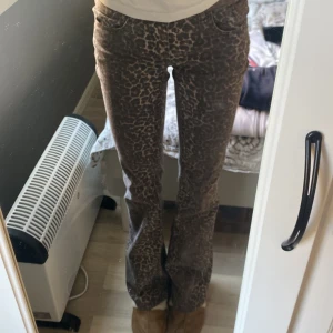 Leopardmönstrade bootcut-byxor från Nelly - Snygga bootcut-byxor från Nelly med leopardmönster i mörkbruna och beige toner. Byxorna har klassisk femficksdesign, normal passform och är tillverkade i ett mjukt bomullsmaterial. Perfekt för dig som vill sticka ut med ett djuriskt print.