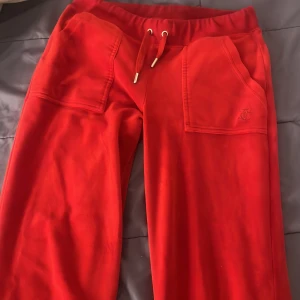 Röda mjukisbyxor Juicy Couture XS - Röda mjukisbyxor från Juicy Couture med broderad JC-logga på fickan. Byxorna har dragsko i midjan, stora fickor framtill och är gjorda i mjukt material som känns riktigt skönt. Perfekta för chill dagar eller när du vill ha en poppig färg på outfiten. Köpta för 1300kr använda typ 2-3 gånger säljer för 600kr
