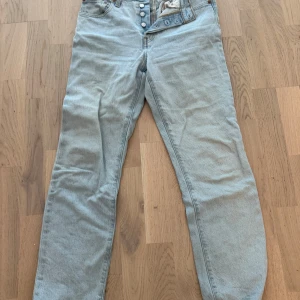Ljusblå Levi's 501 jeans straight fit - Säljer ett par klassiska ljusblå Levi's 501 jeans med raka ben och knäppning framtill. Jeansen har fem fickor och en avslappnad passform. Perfekta för dig som gillar en tidlös denimstil.