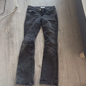 Svarta bootcut jeans från Perfect Jeans - Snygga svarta bootcut jeans från Perfect Jeans i storlek 32. Jeansen har en tvättad look, klassiska femficksdetaljer och bakfickor med lock och knapp. Tillverkade i stretchigt denim för skön passform och stilren vibe.