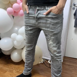 ÄKTA Grå Dsquared2 jeans (Vita detaljer)  - Säljer ett par grå jeans från Dsquared2 Byxorna har raka ben, klassiska fem fickor och Dsquared2-logga på bakfickan. Perfekt för dig som gillar streetstyle. De är 100% äkta!