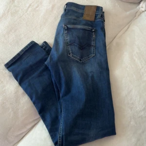 Replay jeans  - Snygga blå jeans från Replay med klassisk femficksmodell och raka ben. Jeansen har en mörk tvätt med lätt slitning framtill och bakficka med diskret söm. Perfekta för dig som gillar en tidlös och avslappnad stil.