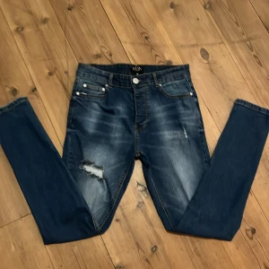 Blå skinny jeans från boohooMAN - Snygga blå skinny jeans från boohooMAN med slitningar och trasiga detaljer på låret. Jeansen har klassisk femficksdesign, smal passform och är tillverkade i stretchigt denim för extra komfort.