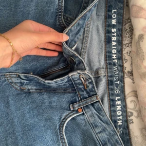 Blå low waist straight jeans - Säljer ett par blå jeans med låg midja och raka ben. Klassisk femficksmodell med dragkedja och knapp framtill. Jeansen har en snygg tvätt och är perfekta för en avslappnad stil.