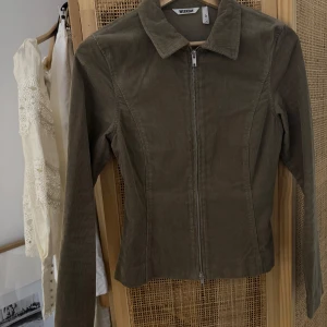 Jacka/tröja i Manchester  - Olivgrön manchesterjacka från Weekday med krage och hel dragkedja framtill. Använd en gång! 