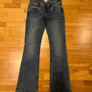 Blå bootcut jeans Gina Tricot 158 - Snygga blå jeans från Gina Tricot i storlek 158, de passar bra på mig som är 162. Modellen har bootcut-ben och klassisk femficksdesign. Jeansen är i ett mjukt denimtyg med lätt slitning och dragkedja framtill. Perfekta för dig som gillar en trendig och avslappnad look.