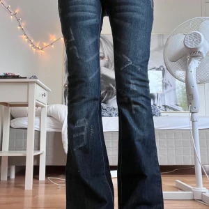 lågmidjade Mörkblå Nude bootcut jeans - TYVÄRR måste jag sälja dessa skitsnygga jeans från Nude i helt nytt skick med lapparna kvar!! eftersom dom är för små för mig. dock har stygnen från baklappen lossnat(se bild) men det var så när jag köpte dom. Jätte low waist och bootcut med coola detaljer över hela jeansen!! storleken på lappen är size 26 length 34.