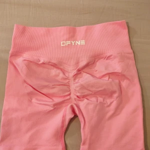 Rosa gymshorts från DFYNE - Säljer ett par ljusrosa gymshorts från DFYNE med hög midja och scrunch-detalj bak. Mjukt och stretchigt material som sitter tight och framhäver formerna. Perfekta för träning eller chill.