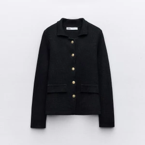 Svart cardigan jacka från Zara - Stilren svart cardigan jacka från Zara med guldknappar framtill och två fickor. Jackan har en klassisk krage och är långärmad, perfekt för en clean och snygg look. Materialet är stickat och ger en mjuk känsla.