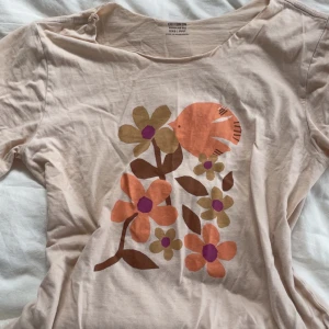 Beige blommig t-shirt från Cotton On - Söt beige t-shirt från Cotton On med färgglatt tryck av blommor på framsidan. T-shirten har korta ärmar och en rund halsringning som jag har själv klippt. Inga defekter eller fläckar💗