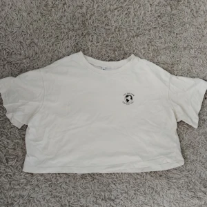 Vit croppad t-shirt med tryck - Vit croppad t-shirt i bomull med svart tryck på bröstet som föreställer en jordglob och texten 'Love Your Earth'. T-shirten har korta ärmar och en loose fit. Ingen lapp för storlek men skulle säga att den passar xs-m ungefär.