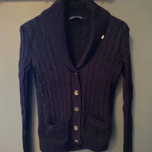  Kofta Polo Ralph Lauren - Snygg mörkblå kofta från Polo Ralph Lauren med grovstickad struktur och kabelstickat mönster. Koftan är liten i storlek och har skada på ena knappen (bild 5)