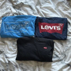 3-pack Levi's t-shirts med logga - Tre snygga t-shirts från Levi's i olika färger: en blå med vit logga, en marinblå med röd och vit logga samt en svart med liten röd logga. Klassisk passform och rund hals. T-shirts som aldrig kommer att användas