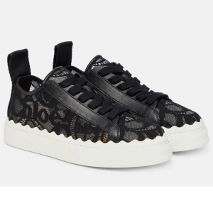 Chloé Lauren svarta spets-sneakers - Säljer ett par Chloé Lauren sneakers i svart spets och skinn med vågig sula och tydlig logga baktill. Skorna har snörning och vit platt sula, samt unika detaljer i mesh och läder. Kommer med originalkartong och dustbag.