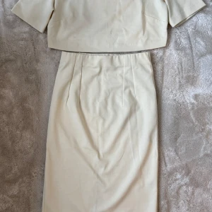 Capri set från Àvora - Snygg croppad topp från Àvora i beige bomullsmix. T-shirtdesign med rund halsringning och korta ärmar. Enkel och stilren modell som är lätt att matcha med olika underdelar. Perfekt för dig som gillar minimalistisk och clean stil.