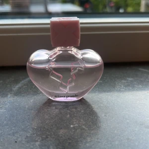 Ariana Grande hjärtformad parfym - En parfym från Ariana Grande. Lätt att ha med sig i väskan för den är rätt så liten. Den innehåller 7.5 ml, men lite använd.
