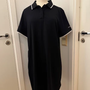 Svart pikéklänning från Röhnisch - Svart kort pikéklänning från Röhnisch med vit kant på krage och ärmslut. Har korta ärmar, 2 knappar framtill och praktisk ficka med dragkedja i sidan. Tillverkad i ett sportigt, lätt material som passar perfekt för golf eller tennis. Använd en ggr. Som ny! Stl XL så säljer jättebilligt! Hämtas i Hägersten om du vill slippa frakt. Var även uppmärksam på när Plick erbjuder fraktfritt ibland på dyrare plagg. Följ mig gärna. Har mycket att lägga ut i olika storlekar! 