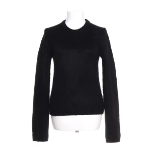 Svart fluffig stickad tröja - Mysig svart stickad tröja med fluffig känsla och rund halsringning. Långärmad modell som passar perfekt när du vill ha en enkel men snygg look. Perfekt att matcha med jeans eller kjol för en stilren vibe.