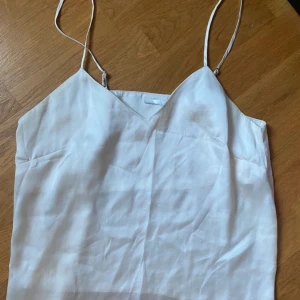 Vit/Beige satinlinne - Säljer en stilren vit/beige satin linne  med tunna axelband och v-ringning. 🎀