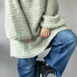 Oversized virkad tröja i ljusgrön ull - Supermysig oversized virkad tröja i ljusgrön nyans. Tröjan har grovvirkar mönster, långa vida ärmar och en loose fit som ger en chill vibe. Perfekt att slänga på sig över jeans för en avslappnad look.
