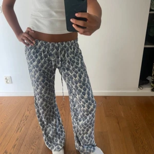 Mönstrade vida linnebyxor från subdued  - Säljer ett par vita linnebyxor med blått mönster och avslappnad passform. Byxorna har låg midja och dragsko i midjan för perfekt passform. Materialet är tunt och luftigt, perfekt för varma dagar. Vida ben ger en chill vibe och de är superbekväma att ha på sig.