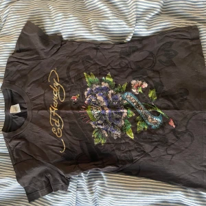 Ed Hardy t-shirt med blommor - Grå t-shirt från Ed Hardy med blommor gjorde i färgglada stenar jätte snygg och den är från tidigt 2000-tal köpt för 550kr säljes för 250kr