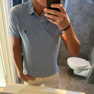 Ljusblå pikétröja från Ralph Lauren - Säljer en stilren ljusblå pikétröja från Ralph Lauren med klassisk krage. Pikén är i riktigt bra skick. Jag är 188cm på bilden. Hör av er vid frågor;)