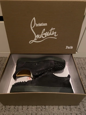 Mörkgråa louboutin med spikar - Säljer ett par feta mörkgråa sneakers från Christian Louboutin med de ikoniska röda sulorna! Jag har använt de en gång och de är i jättebra skick. Skorna är rengjorda så bra som möjligt och fråga gärna frågor!