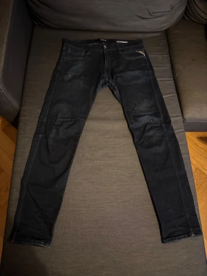 Replay Anbass mörkblåa jeans, 31/32 - Mörkblåa Replay Anbass jeans med klassisk femficksdesign och snyggt läderpatch bak. Slimmad passform och raka ben, tillverkade i mjukt jeanstyg. Perfekta för dig som gillar stilrena och moderna jeans med diskreta detaljer.