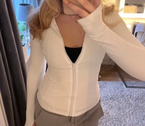 Vit zip-tröja med lång ärm - Säljer en vit,  tröja med dragkedja framtill och långa ärmar. Använd en gång då jag provade den:)