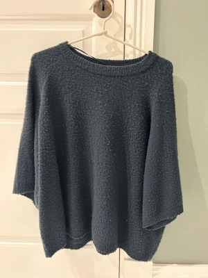 Mörkblå stickad tröja från 157 - Mysig mörkblå stickad tröja från 157 med rund halsringning och trekvartsärmar. Tröjan har en lite loose passform och är perfekt för kyligare dagar. Enkel och stilren design som funkar till många olika looks. Är använd mycket så den är lite nopprig men annars har den inga defekter!