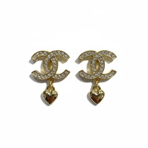  örhängen med hjärthänge - Snygga örhängen i guld med glittrande stenar på det klassiska . Under hänger ett litet hjärta i blankt guld. Perfekt accessoar för dig som gillar lyxig och trendig stil.