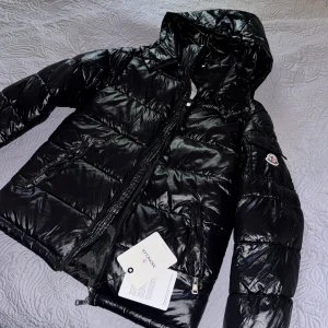 Moncler maya  - Hej jag säljer en svart moncler jacka som e köpt från vinted som jag köpt till min tjej men jackan är för liten för henne och den passar ej bra jackan är i färgen svart fina moncler detaljer finns artikelnummer och scannkod innuti jackan följer med en moncler påse jackan är helt oanvänd och bara stått  kan användas av båda tjej o kill