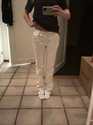 Vita raka jeans med silverdetaljer - Snygga vita jeans med raka ben och silverfärgade nitar vid fickorna. Klassisk femficksmodell med knapp och dragkedja framtill. Passar dig som gillar stilrena och fräscha byxor med lite edge. Perfekt till sneakers eller boots.