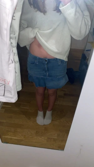 Blå jeanskjol med volang från Superdry - Säljer en blå egen syd jeanskjol från Superdry med volangkant nedtill och klassiska fickor fram och bak. Kjolen har en rå kant längst ner och är i stretchigt denimtyg som sitter snyggt. Perfekt för dig som gillar en cool och avslappnad stil. Den är omsydd från ett par skinny jeans. 