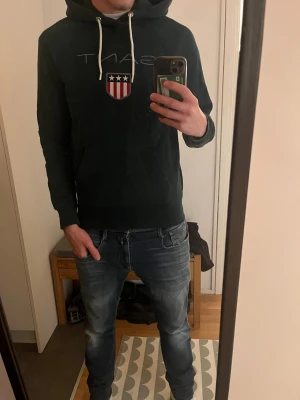 Grön Gant Hoodie - Säljer nu denna Hoodie från Gant i färgen mörkgrön. Hoodien är i storlek S men kan även passa M med lite mer slim modell. Inga defekter. 