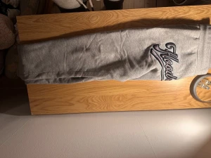 Grå Hoodrich mjukisbyxor med broderi - Säljer ett par grå mjukisbyxor från Hoodrich med snyggt broderat Hoodrich- och Hood Series-märke på benen. Byxorna har snörning i midjan och ribbade muddar vid bensluten. Perfekt för chill och streetwear-stil.