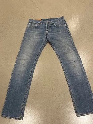 Dondupljusblå jeans med raka ben - Säljer ett par ljusblå jeans från dondup  med klassisk femficksdesign och raka ben. Jeansen har snygga slitningar och detaljerade sömmar på bakfickorna. Materialet är robust denim i bomull och passformen är normal. Perfekt för dig som gillar en avslappnad stil. Går att tvätta 