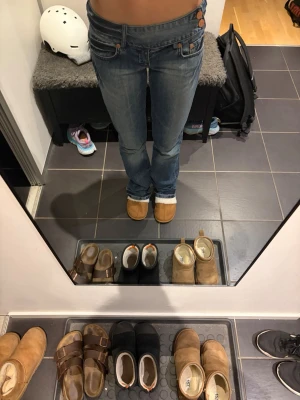 Lågmidjade blå jeans med knappar - Säljer ett par blå jeans med låg midja och snygga kopparfärgade knappar i sidan. Jeansen har klassisk femficksdesign. Jeansen är boutcut och köpta vintage! Dom är i st S/34