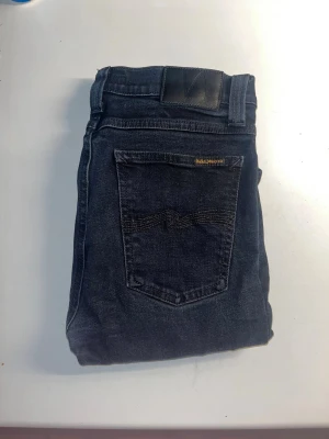 Nudie Jeans - Säljer ett par mörkblå skinny jeans från Nudie Jeans, modell High Kai. Materialet är 99% ekologisk bomull och 1% elastan för extra stretch. Midja 37cm, längd 107cm. JAG SKICKAR EJ FLER BILDER NÄR JAG BÄR JEANSEN! för storleksguide hänvisar jag till måtten och för bättre inblick i passformen rekommenderar jag att googla på modellnamnet. kolla måtten noggrant :) s5