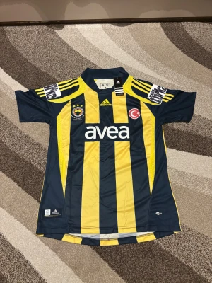Fenerbahce Retro 07-08 Hemmatröja - Denna Fenerbahce Retro 07-08 Hemmatröja är helt ny och aldrig använd. Den är i Storlek M och är perfekt passform. Den har Alex 10 på ryggen för den brasilianska spelaren Alexsandro de Souza. Den har även sponsorn för den tiden COLA TURKA på sidorna. Skit snygg tröja och skön att ha. Vid frågor är det bara att skriva.
