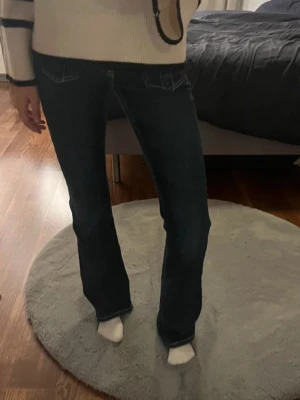 Bootcut jeans i mörkblå denim - Snygga bootcut jeans i mörkblå denim med kontrastsömmar och klassiska fickor både fram och bak. Jeansen har en normal passform och är tillverkade i slitstarkt jeansmaterial. Perfekta för dig som gillar en tidlös och cool look.