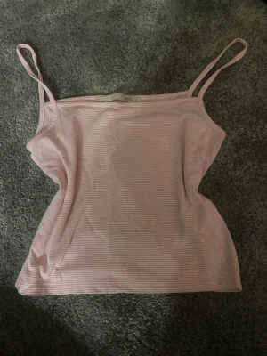 Rosa randig linnetopp från 157 - Säljer en ljusrosa linnetopp från 157 i storlek S. Toppen har tunna axelband och ett diskret randigt mönster i vitt och rosa. Materialet är mjukt och känns som bomull, perfekt för varma dagar. Enkel och stilren design som är lätt att matcha.💕