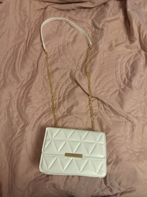 Vit  axelväska med kedja - Snygg vit axelväska med quiltad design och guldfärgad kedja som axelrem. Du kan välja om du vill att den är en axelväska eller handväska❤️
